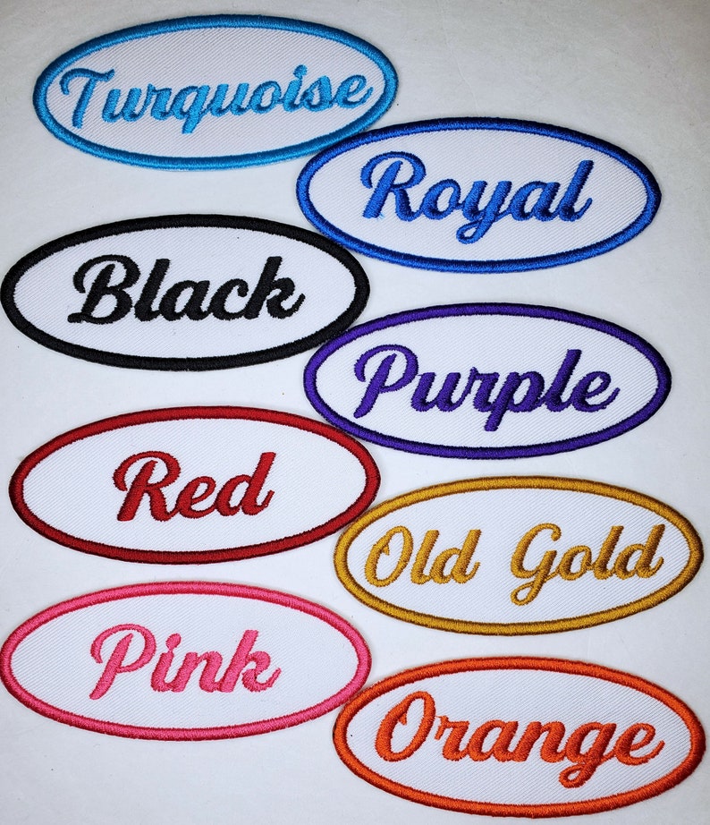 May include: Ten oval-shaped iron-on patches with white backgrounds and embroidered text in various colors. The colors include turquoise, royal blue, black, purple, red, old gold, pink, and orange. The text on the patches reads: Turquoise, Royal, Black, Purple, Red, Old Gold, Pink, and Orange.