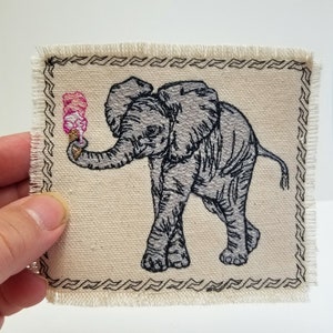 Elefantunge med broderad lapp i canvas, jacka och ryggsäck