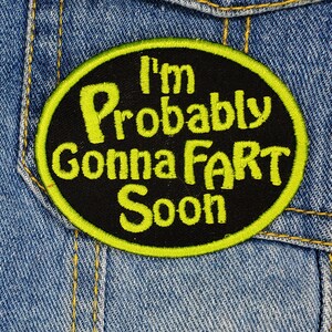 Pode incluir: Um remendo bordado preto e amarelo com o texto "I'm Probably Gonna Fart Soon".