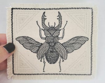 Broderad kanvaslapp med ekorre: Applikation med entomologiska insekter