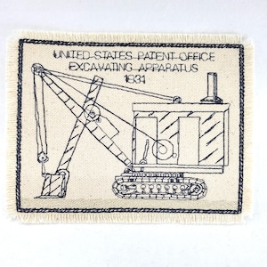 Op de afbeelding: Een zwart-witte lijntekening van een graafmachine op een beige stoffen lap. De tekst "UNITED STATES PATENT OFFICE EXCAVATING APPARATUS 1931" staat boven de graafmachine.