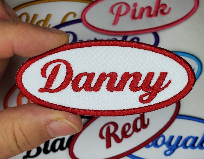 May include: White iron-on patch with red embroidered text that reads "Danny".