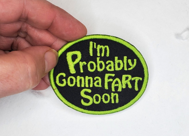Pode incluir: Um remendo bordado preto e verde com o texto "I'm Probably Gonna Fart Soon".