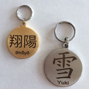 May include: Two gold and silver dog tags with engraved Japanese characters and names. The gold tag has the characters "翔陽" and the name "Shōyō". The silver tag has the character "雪" and the name "Yuki".