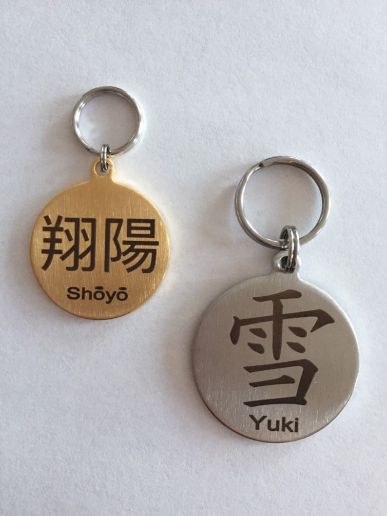May include: Two gold and silver dog tags with engraved Japanese characters and names. The gold tag has the characters "翔陽" and the name "Shōyō". The silver tag has the character "雪" and the name "Yuki".