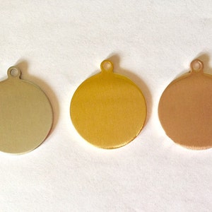 May include: Three round metal tags with a hole at the top. The tags are silver, gold, and copper.