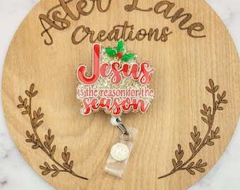 Op de afbeelding: Een rode en gouden glitter kerstbadgehouder met de tekst "Jesus is de reden voor het seizoen" en een hulsttak.