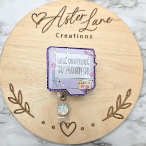 May include: Purple glitter badge reel with a computer monitor design that says "Will Continue to Monitor" and a heart with the text "Nurselife". The reel has a clear, iridescent charm.