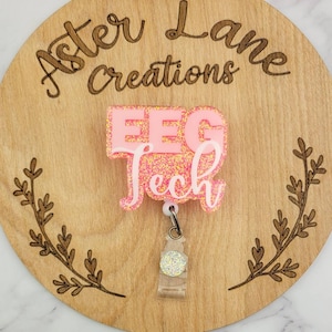 May include: Pink glitter badge reel with the text "EEG Tech" on a wooden background with the text "Aster Lane Creations".