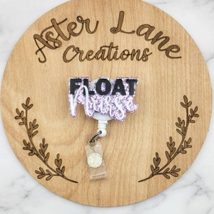 May include: A badge reel with the words "FLOAT Nurse" in black and white glitter lettering. The badge reel is attached to a clear plastic strap with a glittery circle. The badge reel is on a wooden round with the words "Aster Lane Creations".