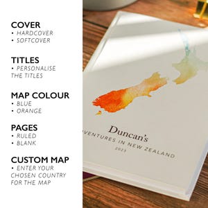 May include: A hardcover journal with a watercolor map of New Zealand in orange and blue. The cover reads "Duncan's Adventures in New Zealand 2023." The journal offers customizable titles, map colors, and page styles.