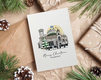 May include: A Christmas card featuring a detailed illustration of Edinburgh landmarks, including the Royal Mile, with a Scottish flag and a snowy Christmas tree. The card is surrounded by pine needles, pine cones, and wrapped gifts.
