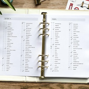 May include: Open planner with gold binder rings, featuring checklists for African and Asian countries. Each country has a checkbox, with some marked. The planner is open to a page with the headings "AFRICA" and "ASIA".