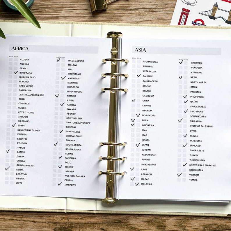 May include: Open planner with gold binder rings, featuring checklists for African and Asian countries. Each country has a checkbox, with some marked. The planner is open to a page with the headings "AFRICA" and "ASIA".