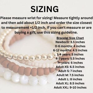 May include: A chart with sizing guidelines for bracelets, ranging from newborn to adult sizes. The chart lists the recommended wrist size in inches for each age group.