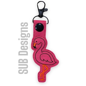 May include: Pink flamingo keychain with a black metal clip. The flamingo is outlined in black and has an orange beak.