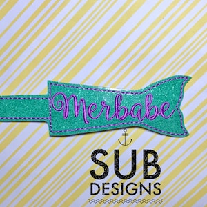 May include: A teal glitter mermaid tail with a purple glitter outline and the word "Merbabe" embroidered in purple thread.