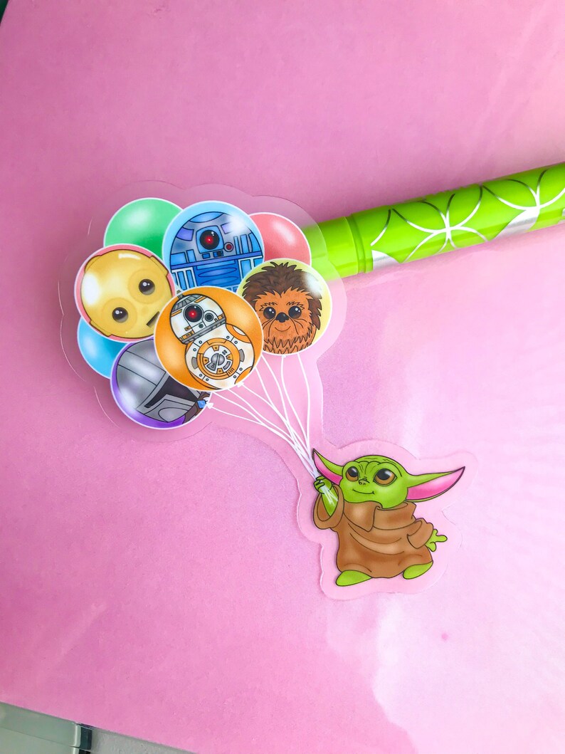 Puede incluir: Un personaje verde con orejas grandes sujetando cinco globos. Los globos son transparentes y presentan im&aacute;genes de dibujos animados de personajes de Star Wars, incluidos R2-D2, Chewbacca y C-3PO.