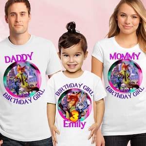 以下が含まれることがあります： ズートピアをテーマにしたデザインの白いTシャツ。シャツには、映画のキャラクターが描かれた円形のグラフィックと、「Daddy」、「Mommy」、「Birthday Girl」の文字がプリントされています。子供のシャツには「Emily」という名前と数字の「3」がプリントされています。