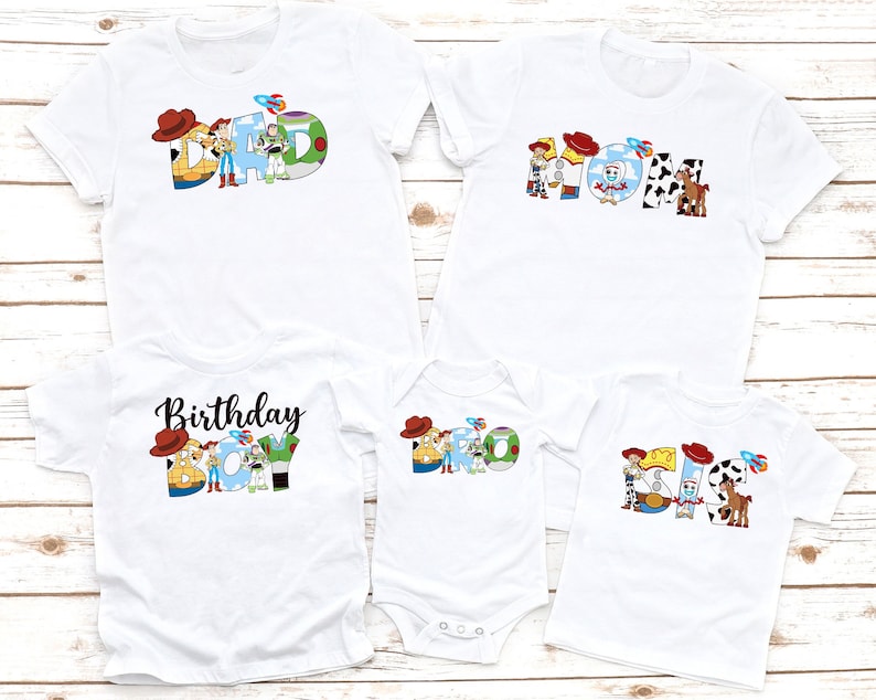 May include: A set of four white t-shirts with a Toy Story theme. The shirts feature the characters Woody and Buzz Lightyear, and the words "Dad", "Mom", "Bro", and "Sis".