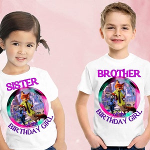 以下が含まれることがあります： 白いTシャツ2枚。「SISTER of the BIRTHDAY GIRL」と「BROTHER of the BIRTHAY GIRL」の文字がピンクと紫で書かれています。それぞれに、ズートピアの漫画のグラフィックが円で描かれています。