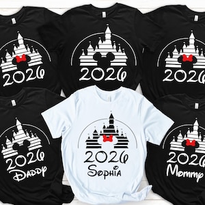 K&ouml;nnte beinhalten: Schwarze und wei&szlig;e T-Shirts mit Schlossdesign, roter Schleife und dem Jahr 2026. Ein wei&szlig;es T-Shirt tr&auml;gt den Namen "Sophia". Andere Shirts tragen die Aufschriften "Daddy" und "Mommy".