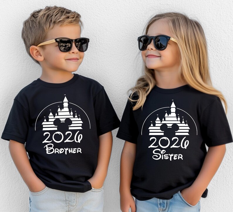 K&ouml;nnte beinhalten: Zwei Kinder tragen schwarze T-Shirts mit einem wei&szlig;en Schloss-Design, Mickey Mouse Ohren und der Jahreszahl 2026. Ein Shirt tr&auml;gt die Aufschrift "Brother", das andere "Sister". Beide Kinder tragen Sonnenbrillen.