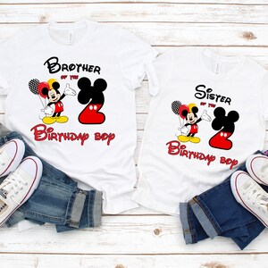 May include: Two white t-shirts featuring Mickey Mouse graphics, red and black balloons, and the text Brother of the Birthday Boy and Sister of the Birthday Boy. Each shirt displays a large number two in red and black, paired with blue jeans.