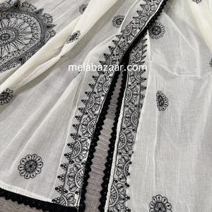 Pode incluir: Tecido branco com bordados pretos intrincados e uma delicada borda de renda preta. O design apresenta padr&otilde;es florais e geom&eacute;tricos, com o texto "melabazaar.com" vis&iacute;vel.