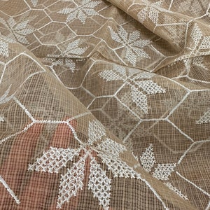 Pode incluir: Tecido bege transparente com um padr&atilde;o geom&eacute;trico branco bordado de hex&aacute;gonos e flores em forma de estrela.