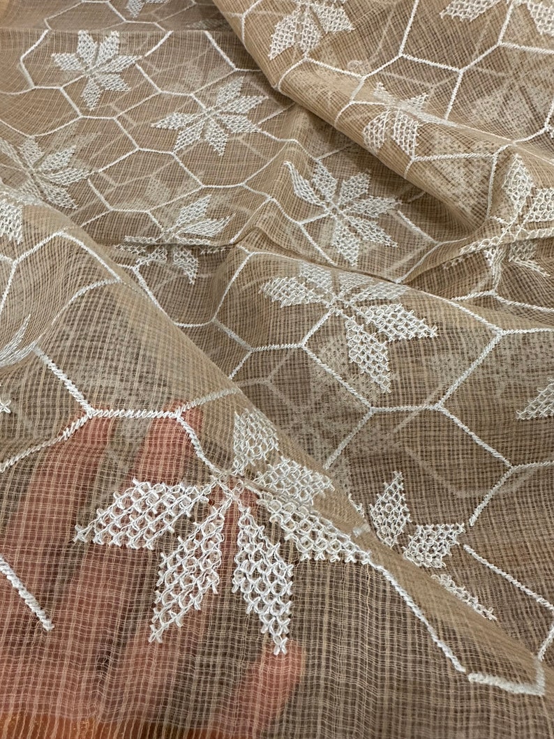 Pode incluir: Tecido bege transparente com um padr&atilde;o geom&eacute;trico branco bordado de hex&aacute;gonos e flores em forma de estrela.