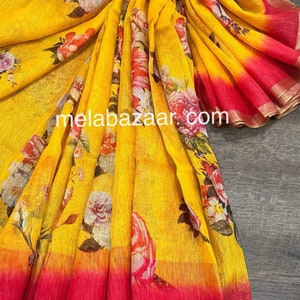May include: A yellow linen saree with a floral print and a pink ombre effect at the bottom. The saree has a gold border.
