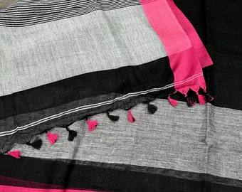 Peut inclure: Un sari en lin rayé blanc et noir avec une bordure noire et une garniture rose. Le sari a des glands sur la bordure.