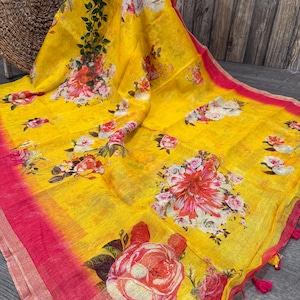 May include: A yellow linen saree with a pink border and floral print. The saree has a gradient effect, with the yellow fading to pink at the bottom.