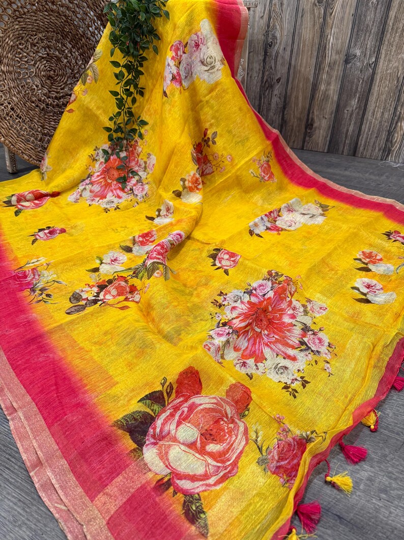 May include: A yellow linen saree with a pink border and floral print. The saree has a gradient effect, with the yellow fading to pink at the bottom.