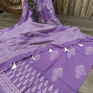 May include: A purple cotton fabric with white block printed designs of leaves and geometric patterns. The fabric has tassels on the edges.