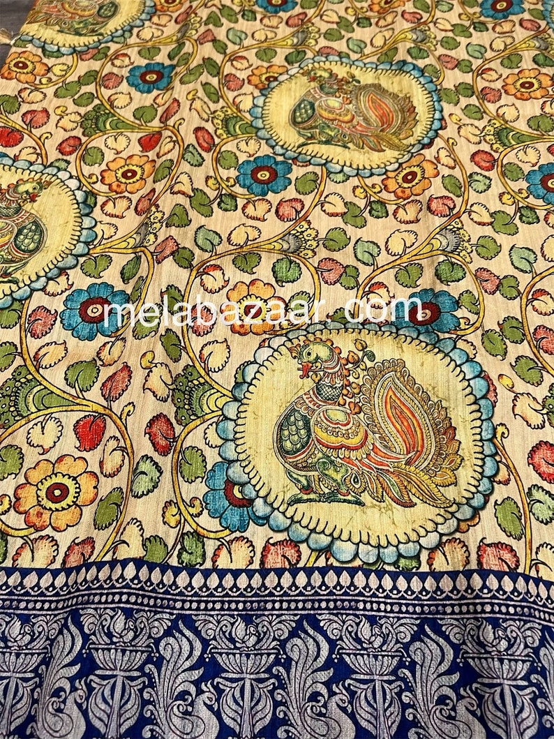 May include: A cream-colored fabric with a repeating pattern of peacocks, flowers, and leaves. The fabric has a blue and silver border with a paisley design.
