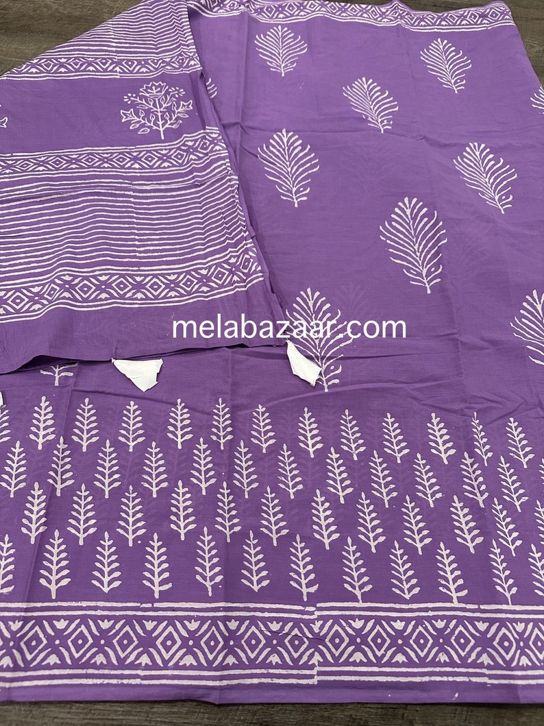 May include: Purple cotton fabric with a white block print design featuring leaves and geometric patterns. The fabric has a subtle sheen and a soft texture.