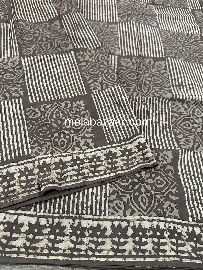 Puede incluir: Una tela de algod&oacute;n marr&oacute;n y blanco con un patr&oacute;n repetitivo de rayas y dise&ntilde;os florales. La tela tiene un brillo sutil y una textura suave.