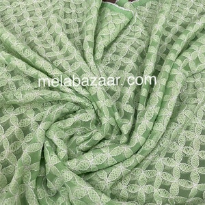 May include: A light green fabric with a white floral embroidery pattern. The fabric is sheer and has a delicate texture.
