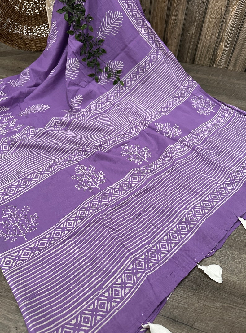 May include: A purple cotton fabric with a white block print design. The fabric features a repeating pattern of leaves and geometric shapes.