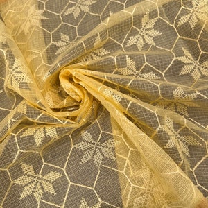 Pode incluir: Um tecido transparente amarelo claro com um delicado padr&atilde;o bordado de estrelas e um design de favo de mel.