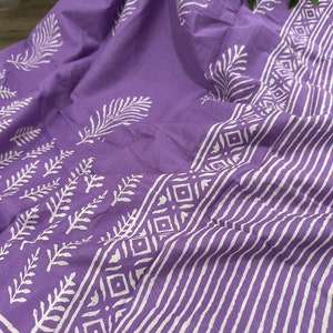 May include: Purple cotton fabric with a white block print design featuring leaves and geometric patterns. The fabric is folded and has a soft, textured feel.