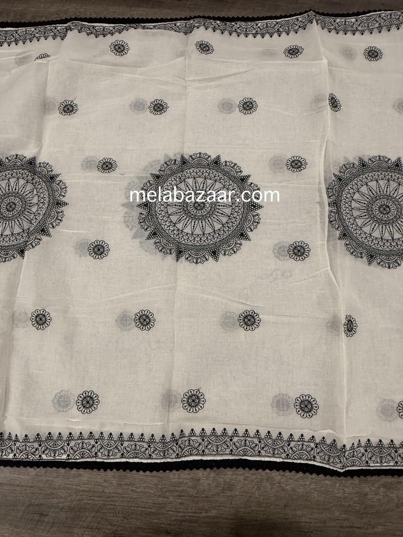 Pode incluir: Tecido branco com um padr&atilde;o floral preto repetido e grandes desenhos de mandala circulares. O texto "melabazaar.com" &eacute; vis&iacute;vel. As bordas s&atilde;o adornadas com uma borda preta.