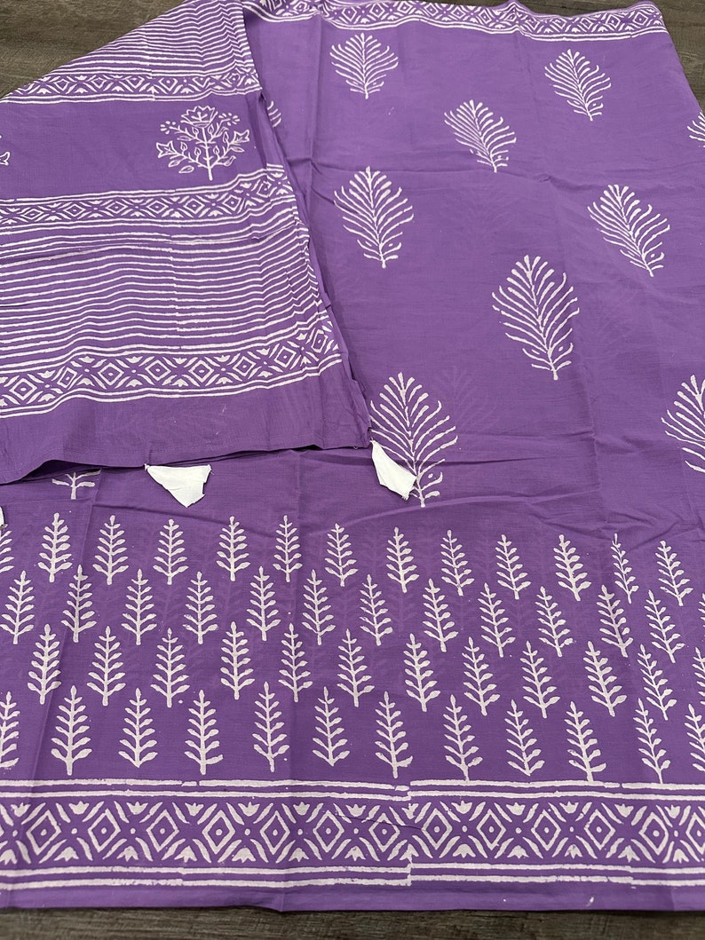 May include: Purple cotton fabric with a white block print design. The fabric features a repeating pattern of leaves and geometric shapes.