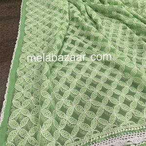 May include: A light green sheer fabric with a white embroidered floral pattern. The fabric has a white crocheted trim around the edges. The text "melabazar.com" is visible in the center of the image.