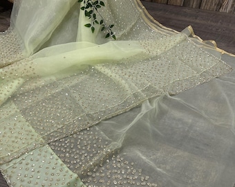 May include: A pale lime green sheer fabric drape featuring an intricate pattern of small, reflective silver-toned embellishments scattered across the surface. The fabric has a finished border with a thin, metallic gold-toned trim along the edge.