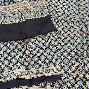 Könnte beinhalten: Ein schwarzer und blauer Stoff mit geometrischem Muster. Der Stoff hat an jedem Ende eine Quaste.