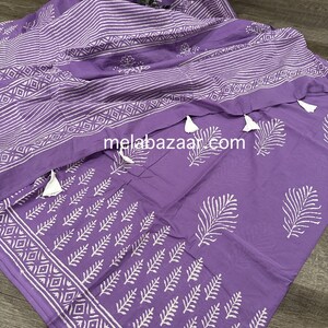 May include: Purple cotton fabric with white block printed designs of leaves and geometric patterns. The fabric has tassels on the edges.