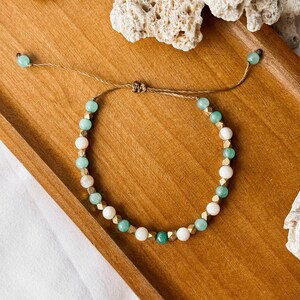 Puede incluir: Una pulsera de cuentas con cuentas redondas alternas de color verde menta y blanco, intercaladas con peque&ntilde;os espaciadores met&aacute;licos dorados facetados. La pulsera se asegura con un cord&oacute;n marr&oacute;n y tiene dos cuentas verde menta en los extremos.